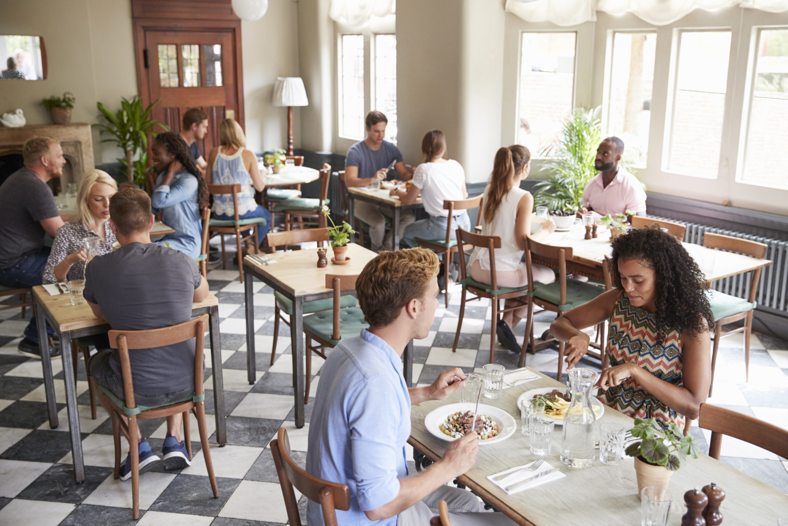 Customers Enjoying Meals In Busy Restaurant